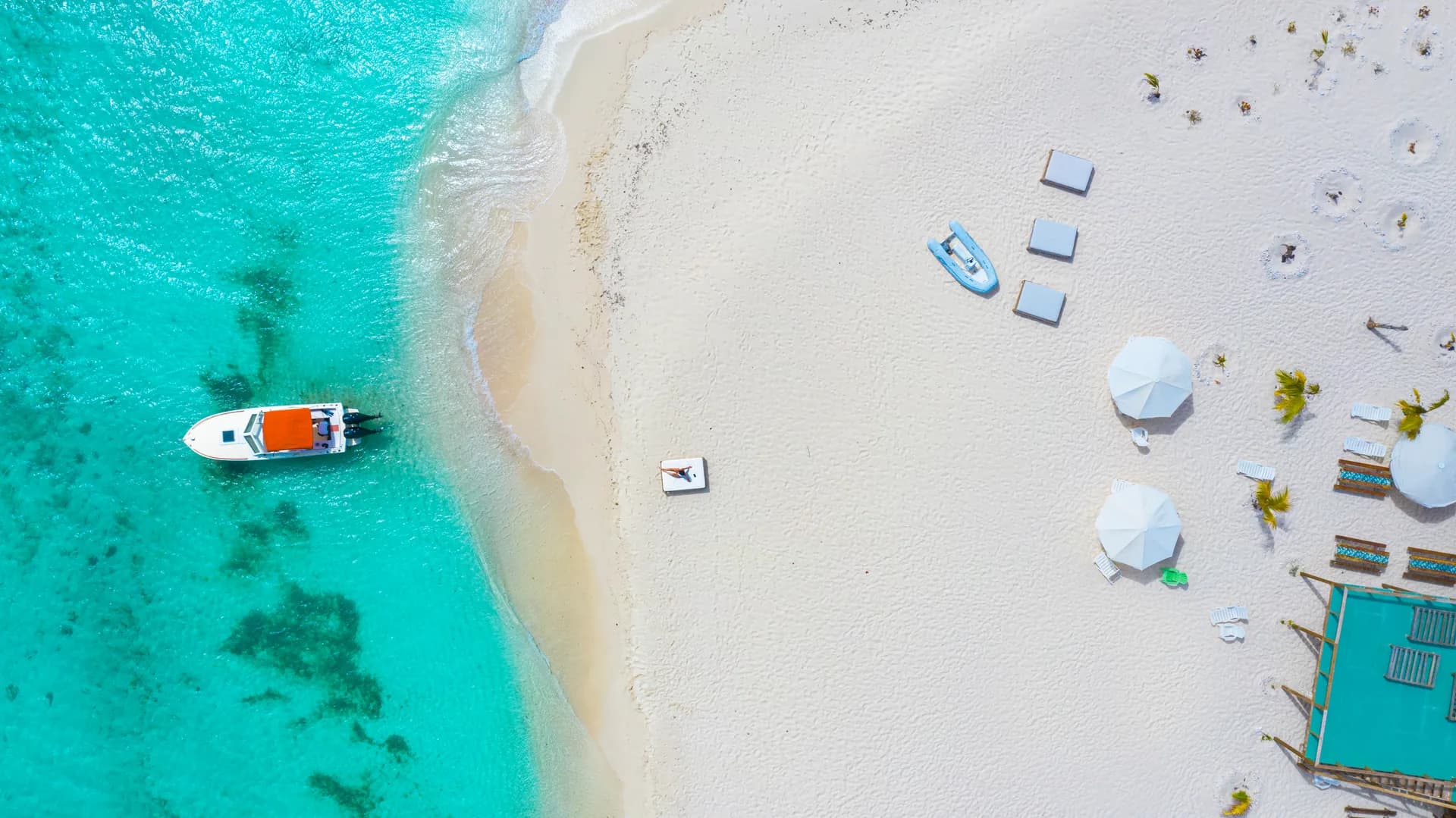 A boat beside the white sand and beach umbrellas on Sandy Island