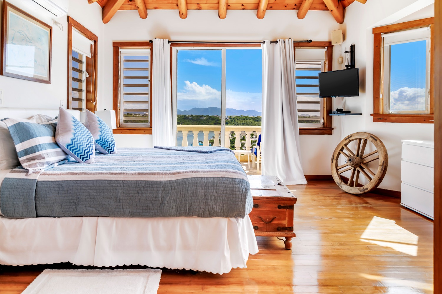 Bright bedroom with blue accents and balcony at Spyglass Hill Villa