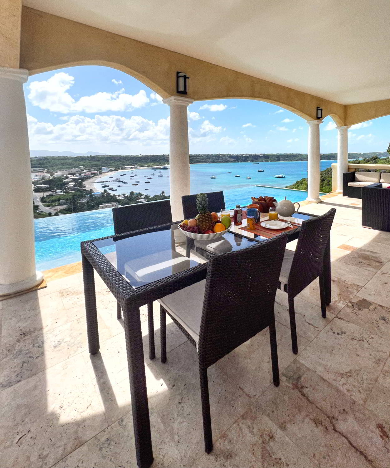 Covered dining terrace with cream columns and blue water views