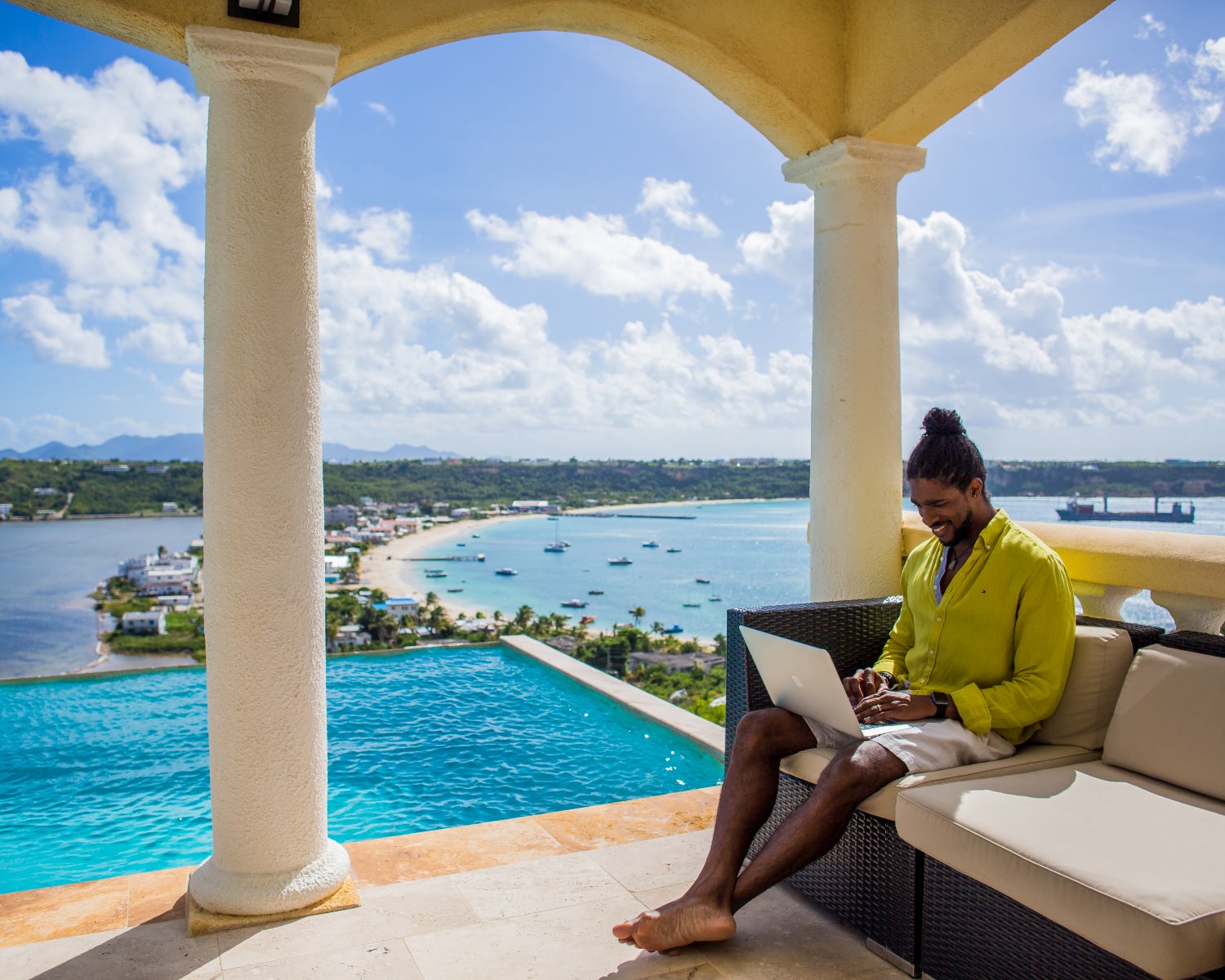 Guest relaxing on a shaded terrace beside the blue pool